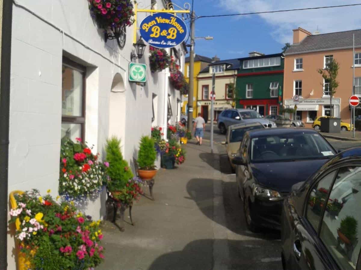 Ben View House B&B exterior with colorful flower boxes lining a street with parked cars.