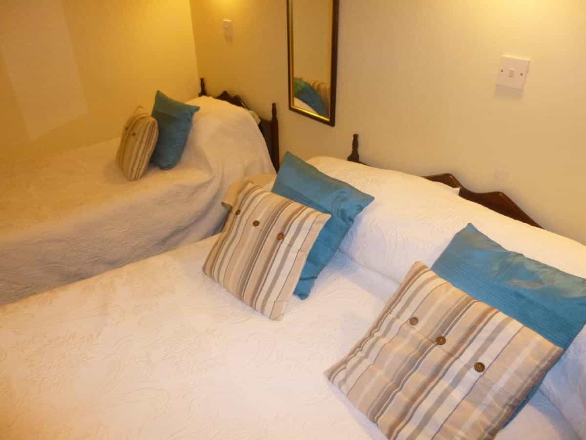 Twin beds with white bedding, turquoise pillows, and striped accent cushions in a warmly lit room.