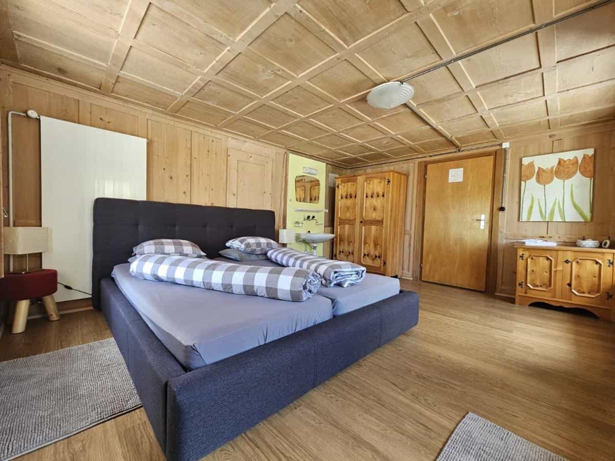 Hotel room with wood paneling, coffered ceiling, and a dark fabric bed frame in Hotel Dalla Posta, Disentis.