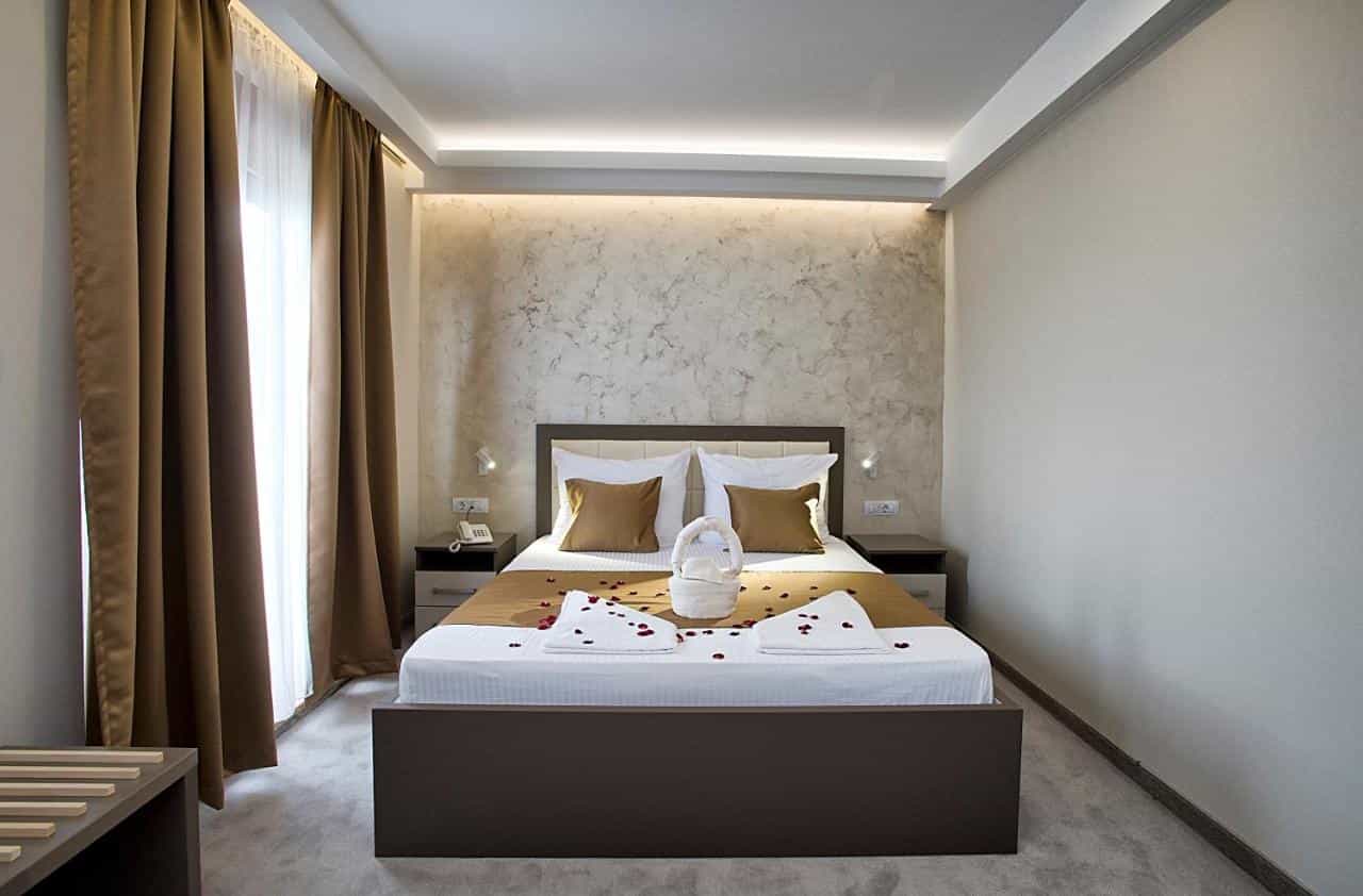 Hotel room at Hotel Fobra Podgorica with bed decorated with rose petals and towel swan.