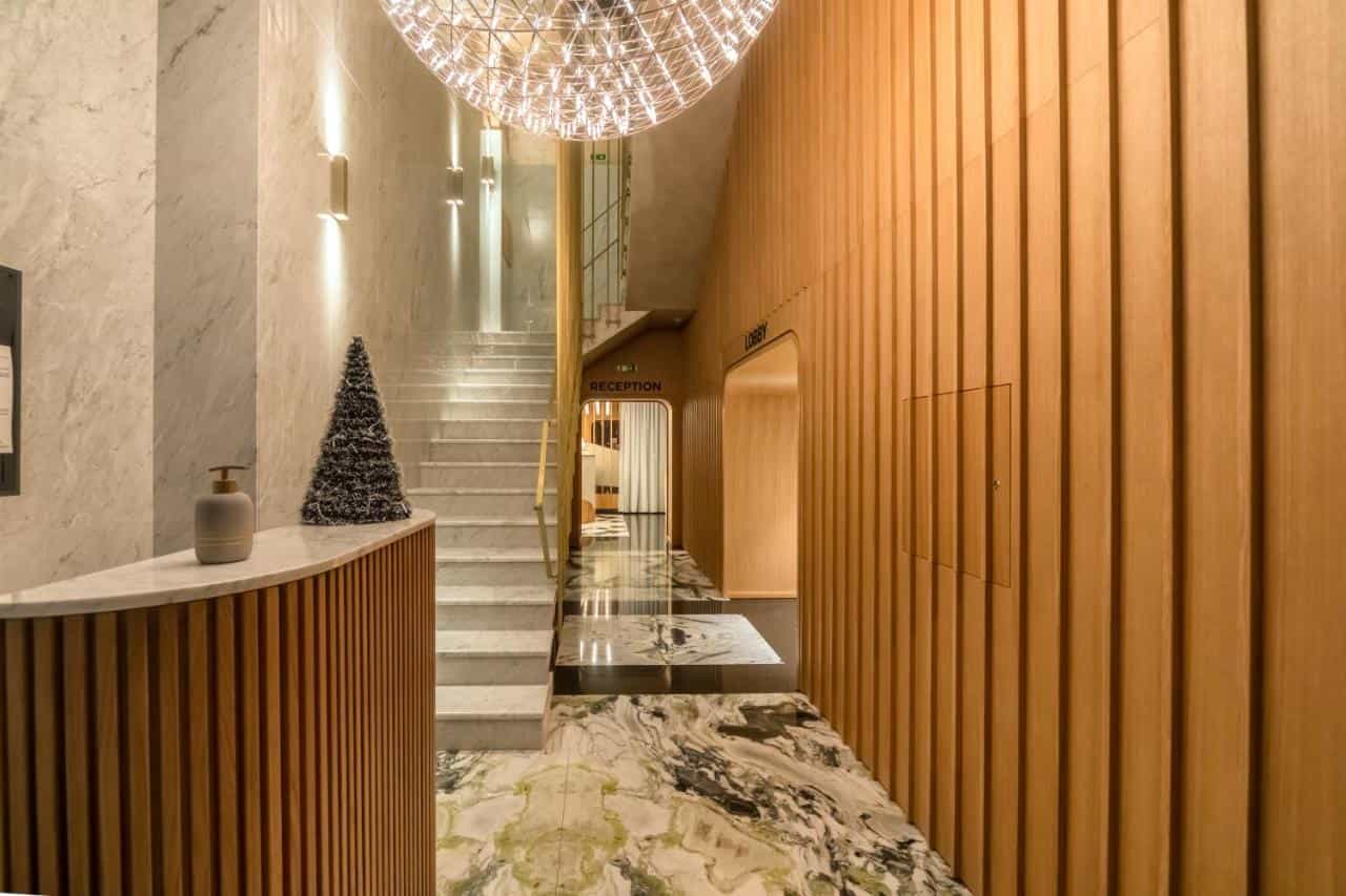 Hotel Agape bar reception area with marble stairs, wood paneling, and modern chandelier.
