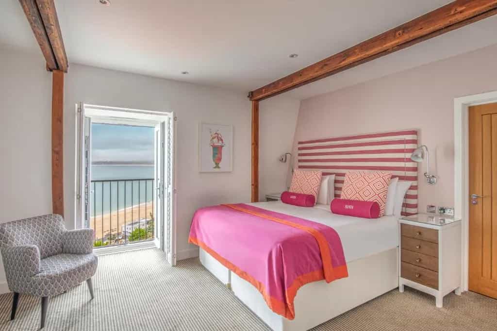 Bedroom with pink bedding and balcony view of beach and sea