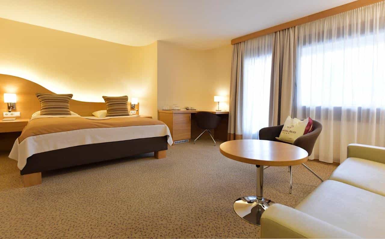 Seehotel Rust hotel room with large bed, desk, and seating area by window