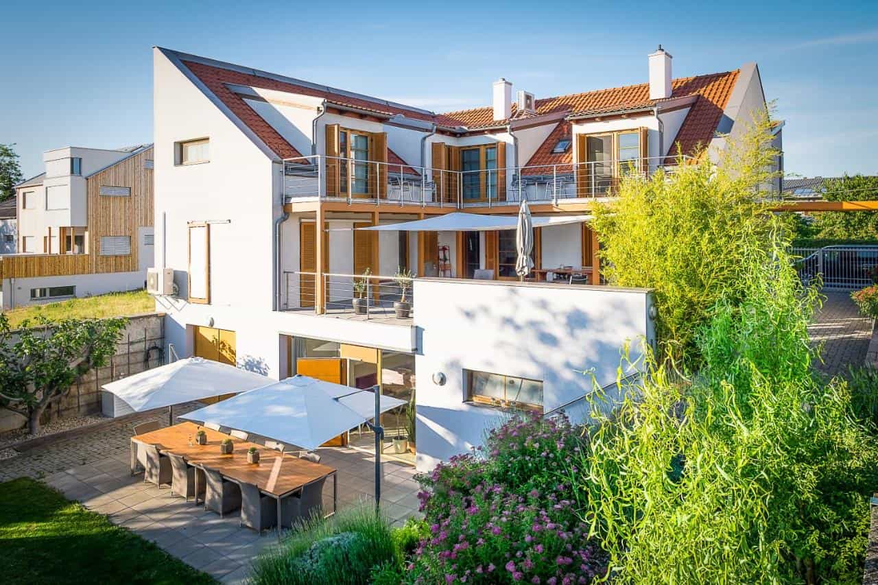 White guesthouse with balconies and outdoor dining patio with large umbrellas, SCHEIBER-Wein-&-Gästehaus.