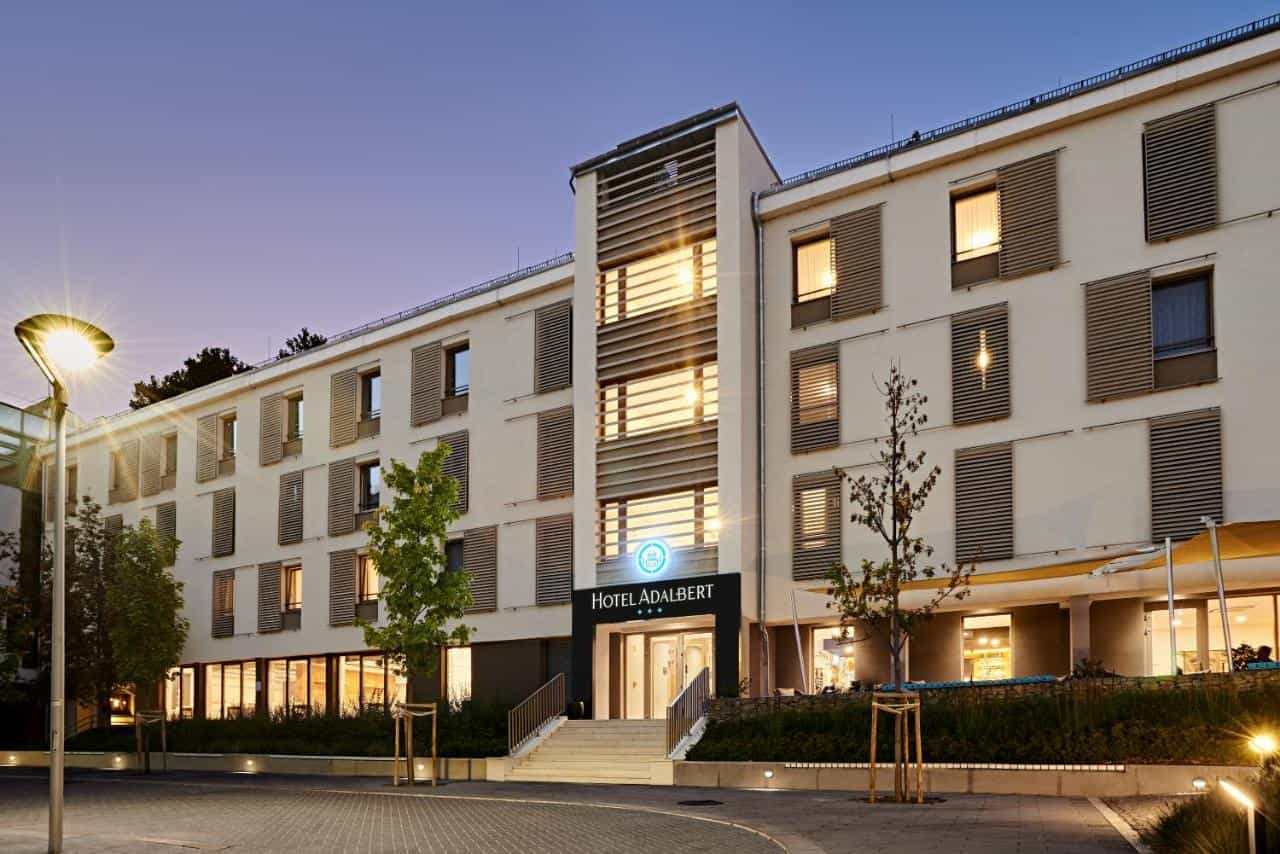 Hotel Adalbert building exterior at dusk with illuminated entrance and street lamp