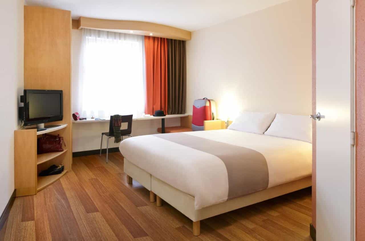 Ibis hotel room in Bratislava Centrum with wood floor, window, and bed.