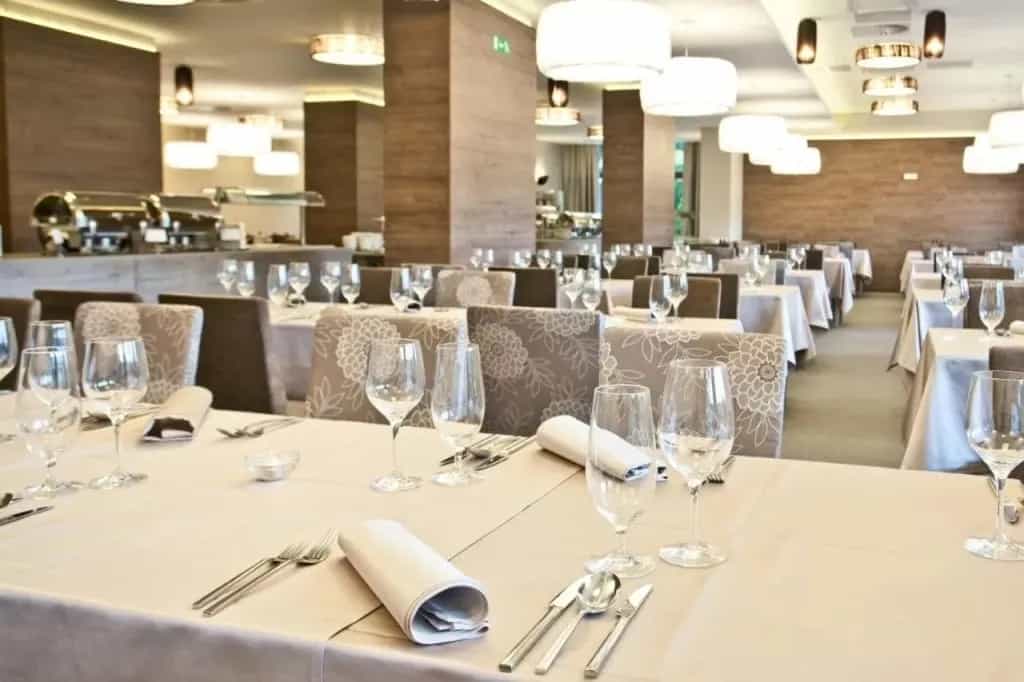 Set dining tables with wine glasses in the Hotel Astoria breakfast area.