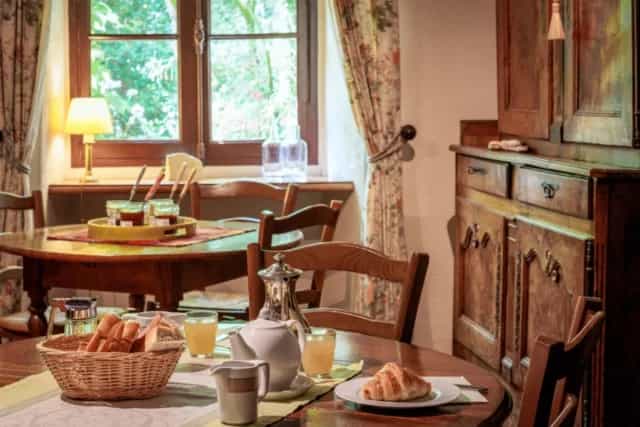 Breakfast table set with bread, croissant, and juice in a rustic dining room at Hotel Diderot.