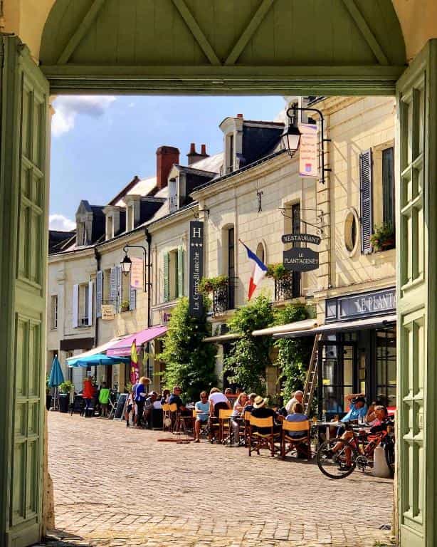 Outdoor cafe dining on a cobblestone street in a historic French town.