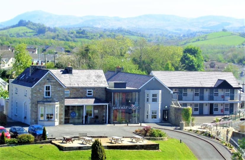 Gateway Lodge building with picnic tables, set against rolling green hills and mountains.