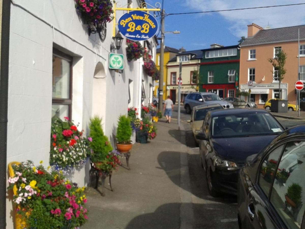 Ben View House B&B exterior with colorful flower boxes lining a street with parked cars.