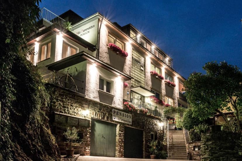 Illuminated Pension Villa Tummelchen at night with bicycle decoration and stone facade in Cochem.