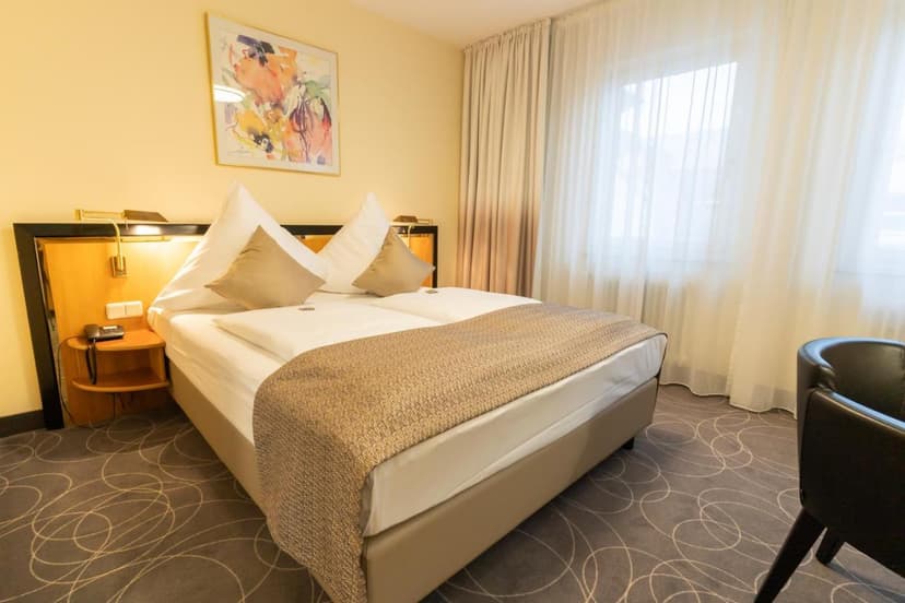 Hotel room at Hotel am Stadtgarten in Radolfzell-am-Bodensee with double bed and bright window.