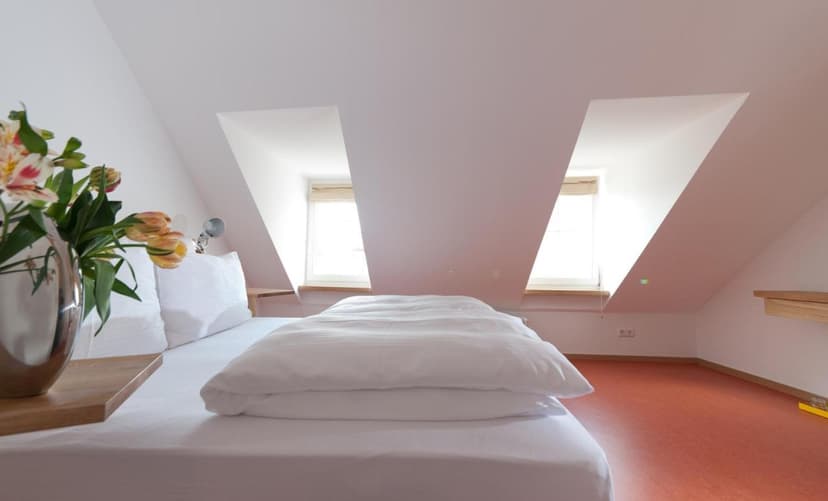 Attic hotel room at Lindau Hotel Engel with white bedding and slanted windows
