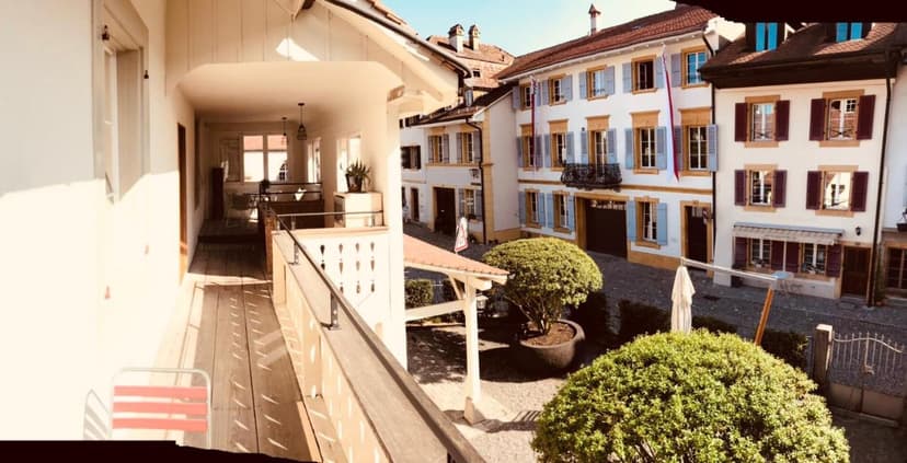 Wooden balcony view over courtyard toward historic buildings in Murten.