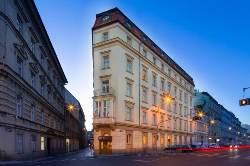 Hotel building on street corner in Prague at dusk with light trails from traffic.