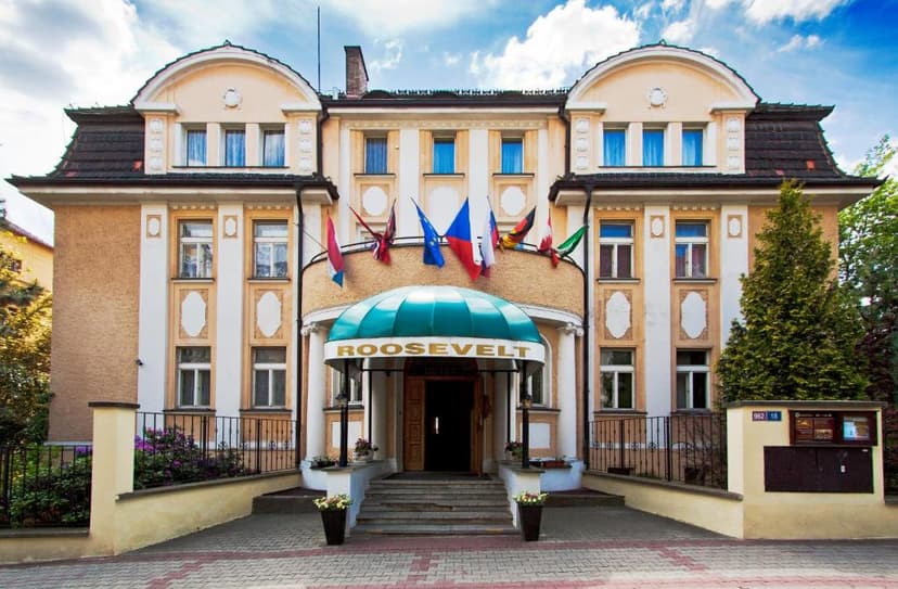 Hotel Roosevelt entrance with green awning, flags, and steps under a blue sky