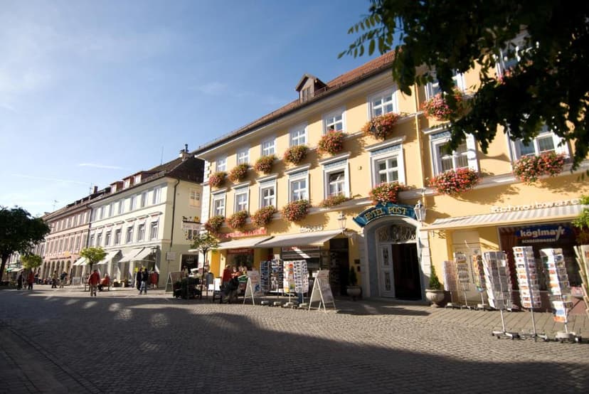 Hotel Post building with flower boxes on a sunny cobblestone street in Murnau.
