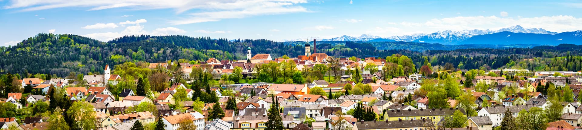 Town of Schongau nestled in green hills with snow-capped Alps visible in the distance