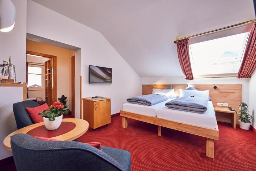 Cozy hotel room with twin beds, seating area, and sloped ceiling in Garmisch.
