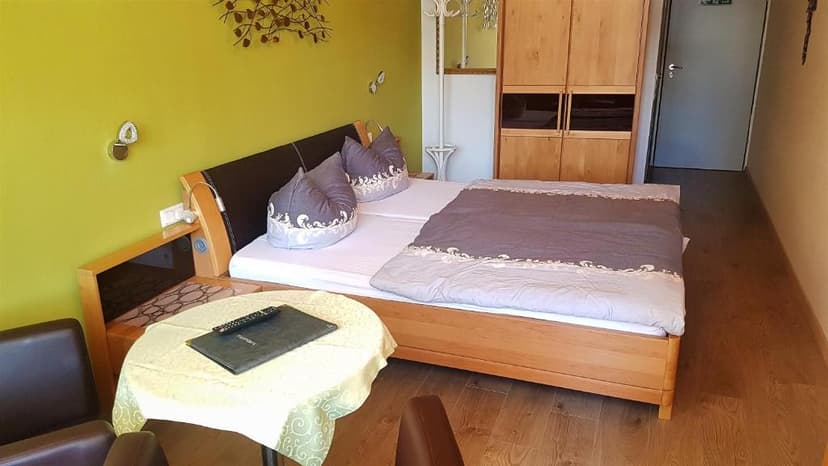 Hotel room with wooden bed, lime green wall, and small table with laptop.