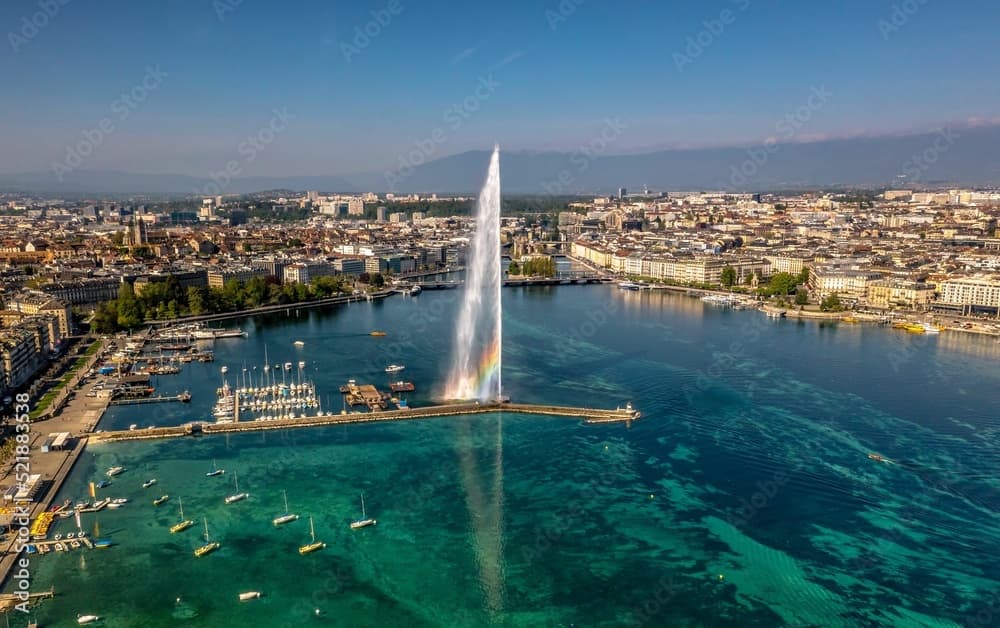 Jet d'Eau fountain spraying high over Lake Geneva with city and boats visible