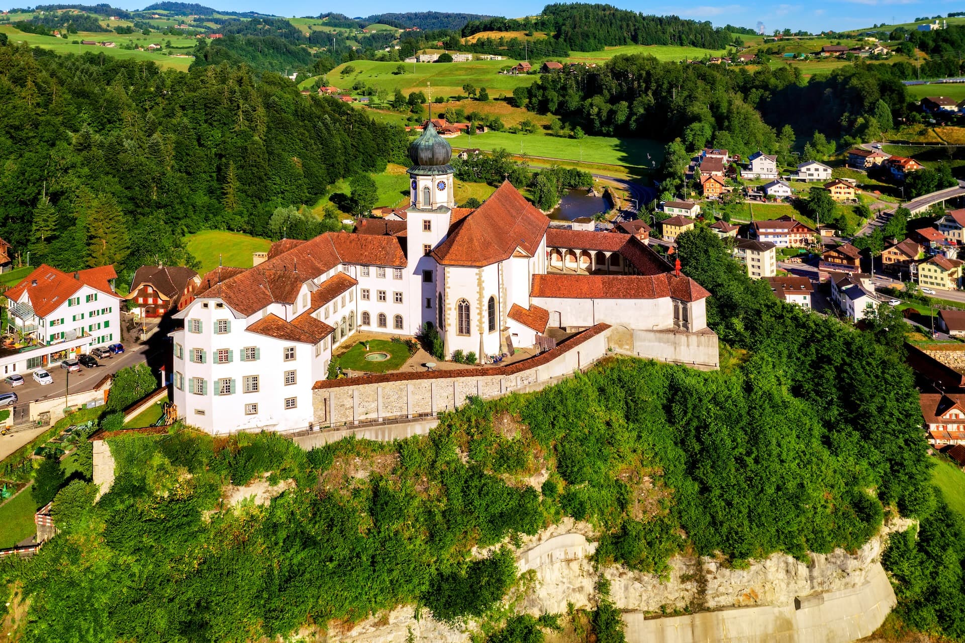 Werthenstein Monastery in Lucerne canton, Switzerland, on a green hillside overlooking a village.