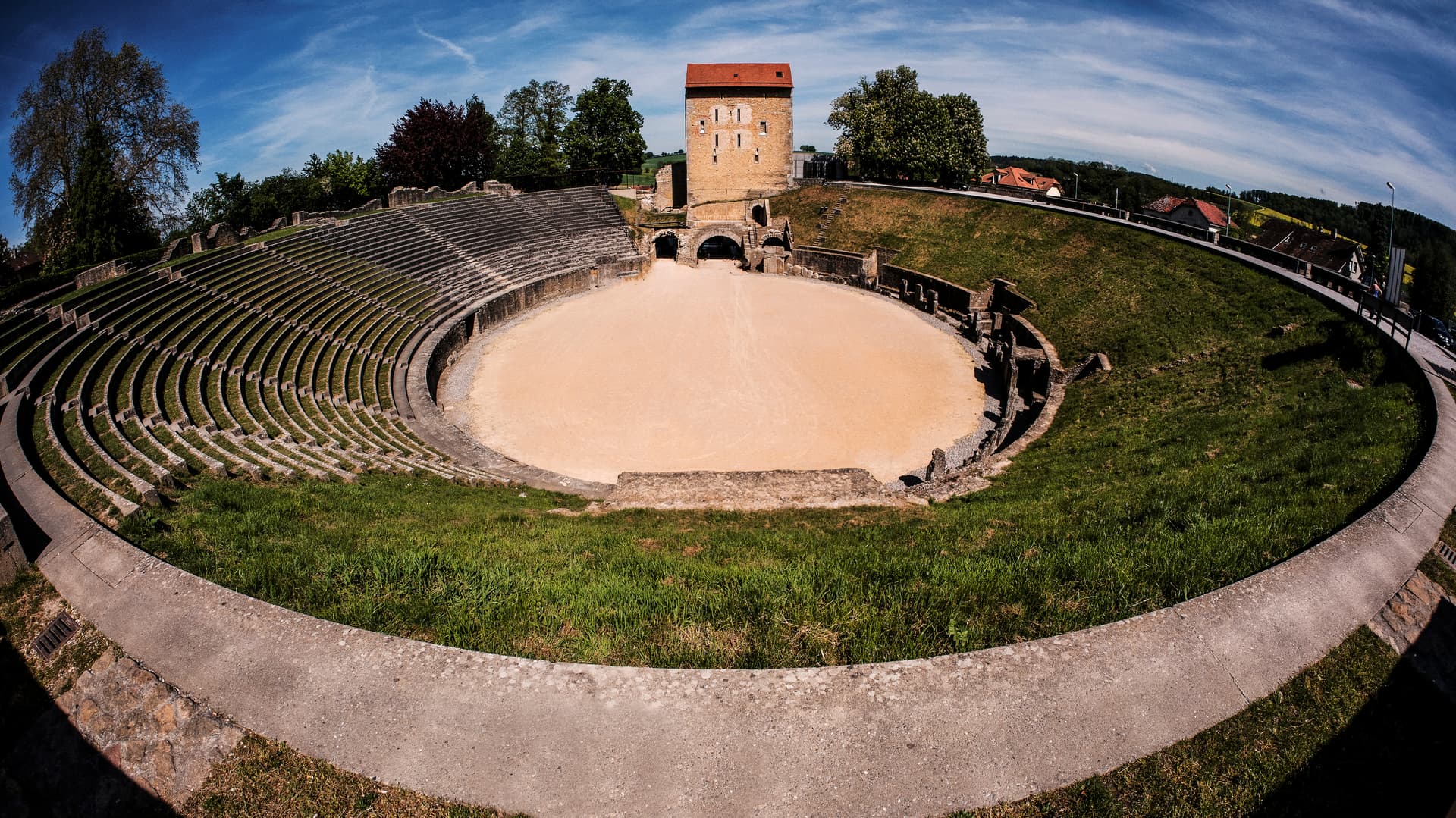 Roman amphitheater ruins with tiered seating and a central arena in Avenches, Switzerland.