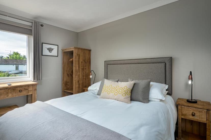 Bedroom in Cairngorm Guest House with wooden furniture and highland cow art