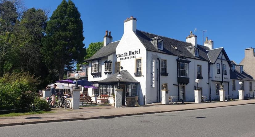 Garth Hotel restaurant with white facade and dark roof, outdoor seating, and bicycles parked.