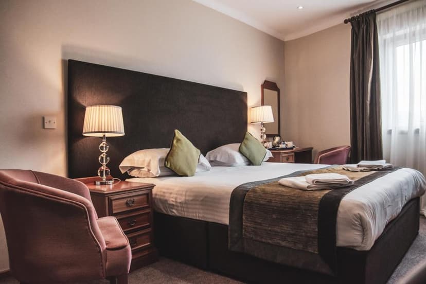 Bedroom in The Angus Hotel & Spa with large bed, side tables, and window with curtains.