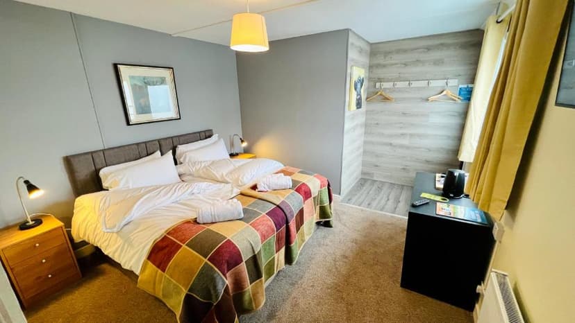 Cozy inn room with twin beds, colorful plaid blanket, and modern gray walls.