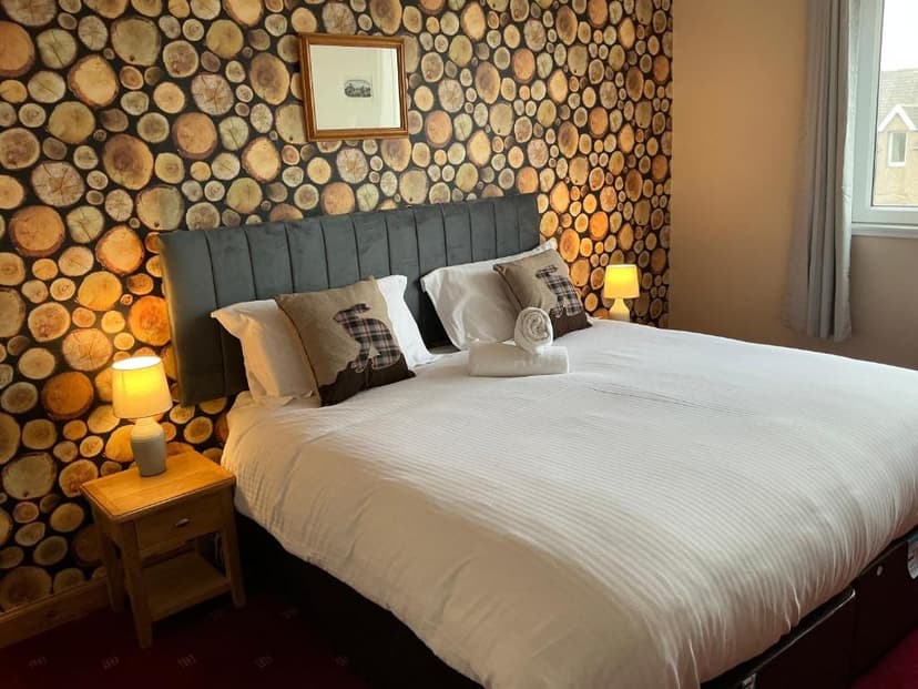 Bedroom with log slice wallpaper, white duvet, and rabbit-themed throw pillow in John O'Groats room.