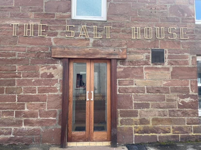 The Salt House" gold lettering above wooden double doors set in a red sandstone brick building facade.