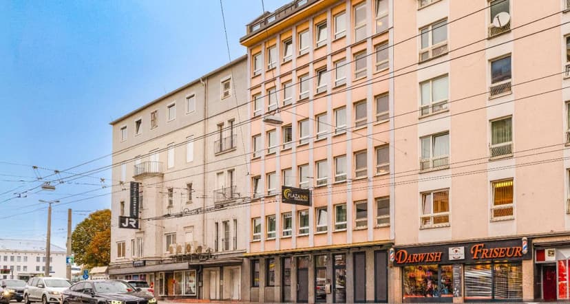 Plaza Inn hotel facade on street with traffic and shops in Salzburg City