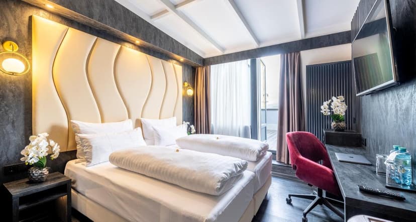 Modern hotel room with twin beds, beige headboard, and balcony access in Salzburg.