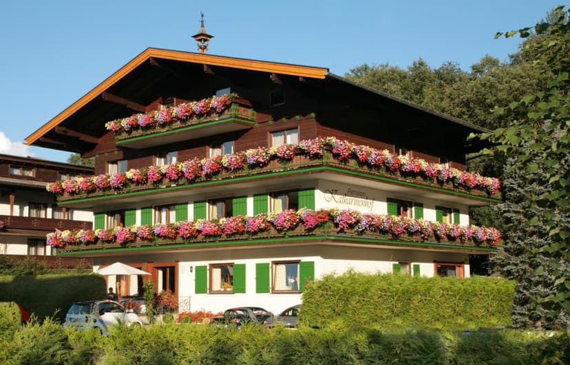 Alpine pension building with wooden balconies overflowing with colorful flowers, Kaprun.
