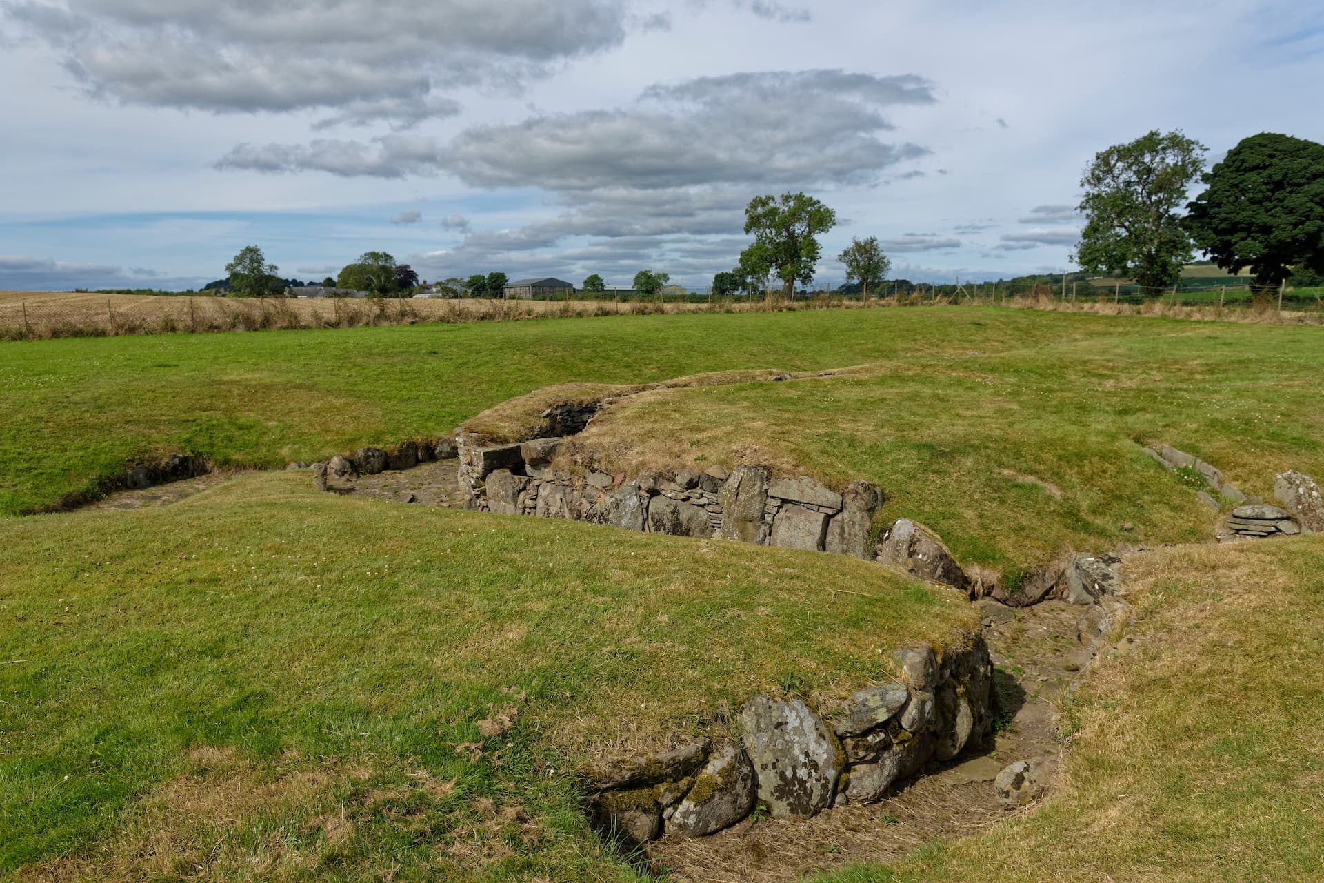 Carlungie Earth House ruins with dry stone walls in a grassy field near Dundee.