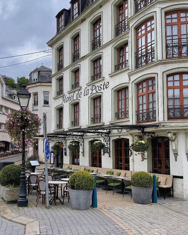 Outdoor dining terrace for Hotel de la Poste on a cobblestone street with potted greenery.