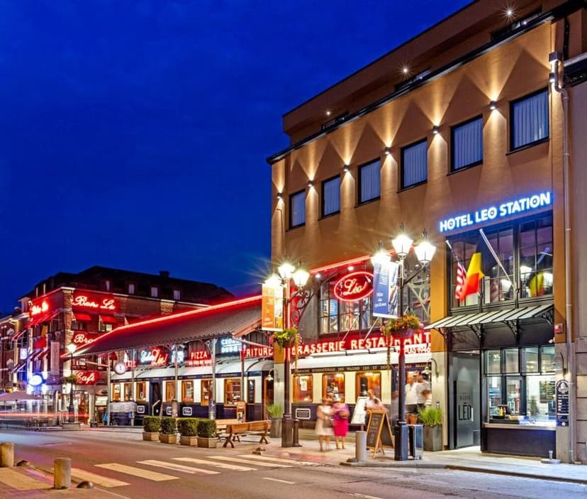 Hotel Leo Station and illuminated restaurants on a city street at dusk with people walking