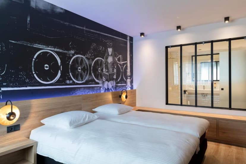 Hotel bedroom with white bedding, wood headboard, and black and white train mural.