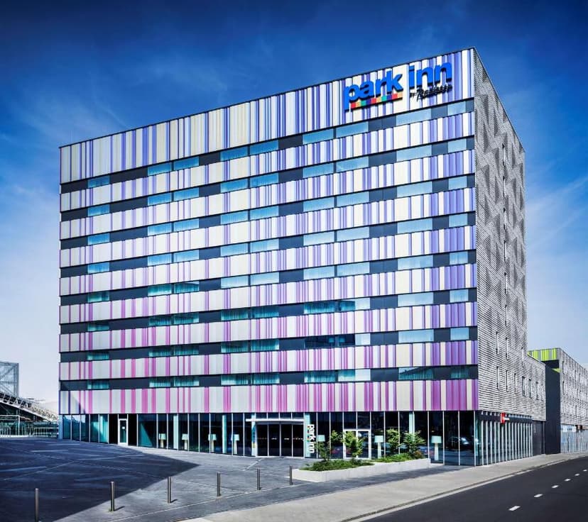 Park Inn by Radisson hotel building with colorful striped facade under a clear blue sky.