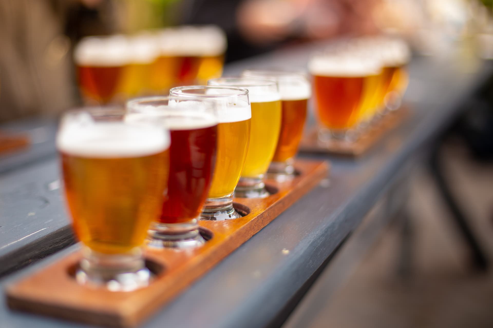 Beer tasting flight with various shades of beer on a wooden paddle outdoors
