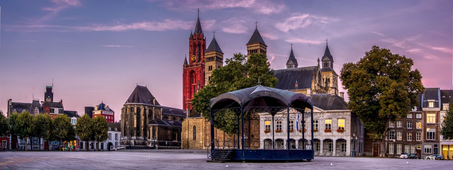 Historic town square with large church and bandstand at sunset in European city
