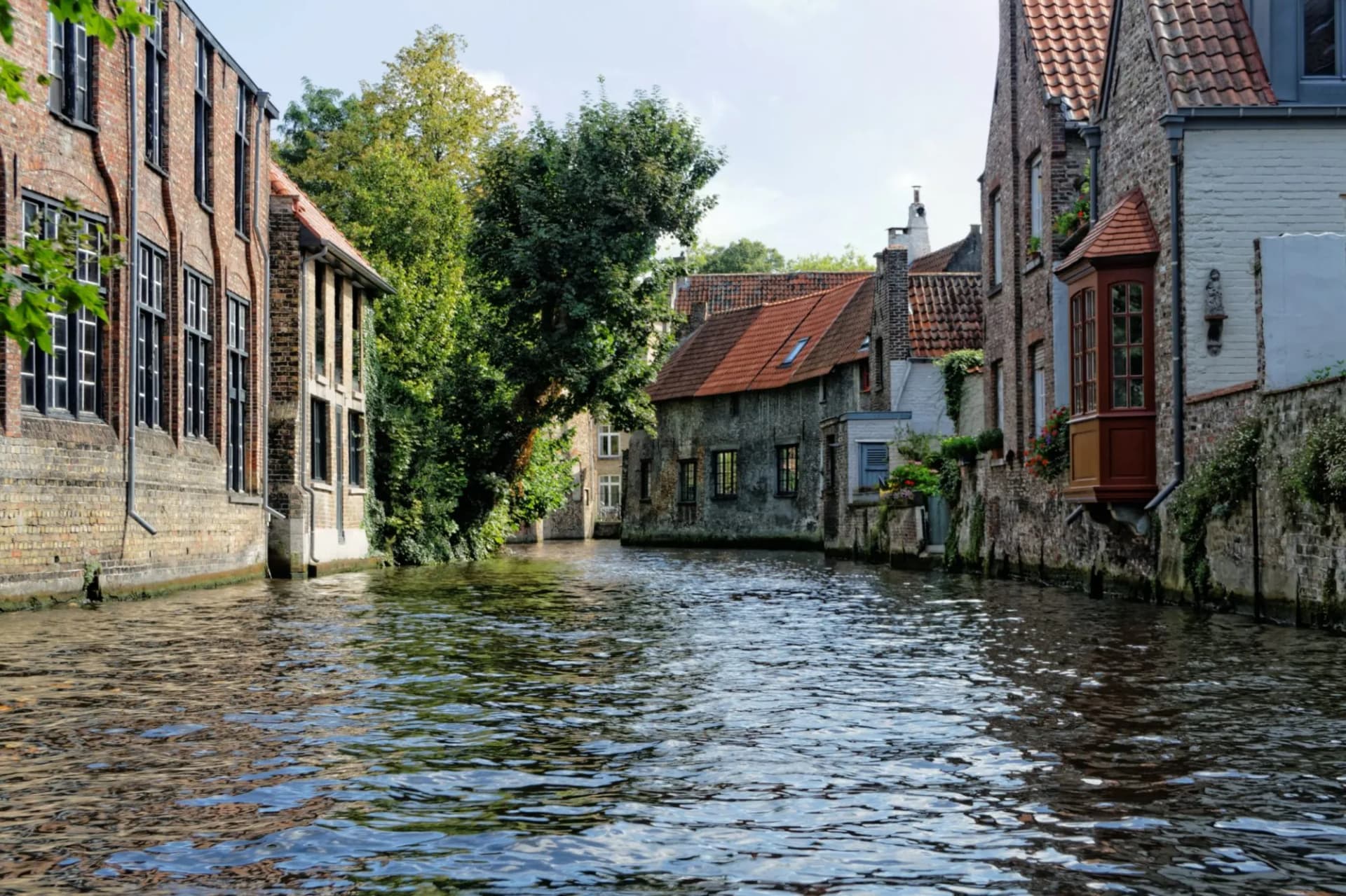 Canal du Nord with historic brick buildings and lush green trees along the water.