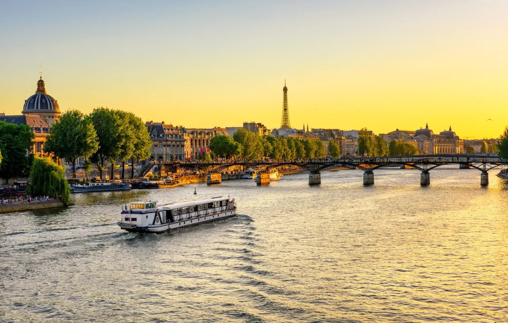 Tour boat on the Seine River in Paris with the Eiffel Tower visible at sunset