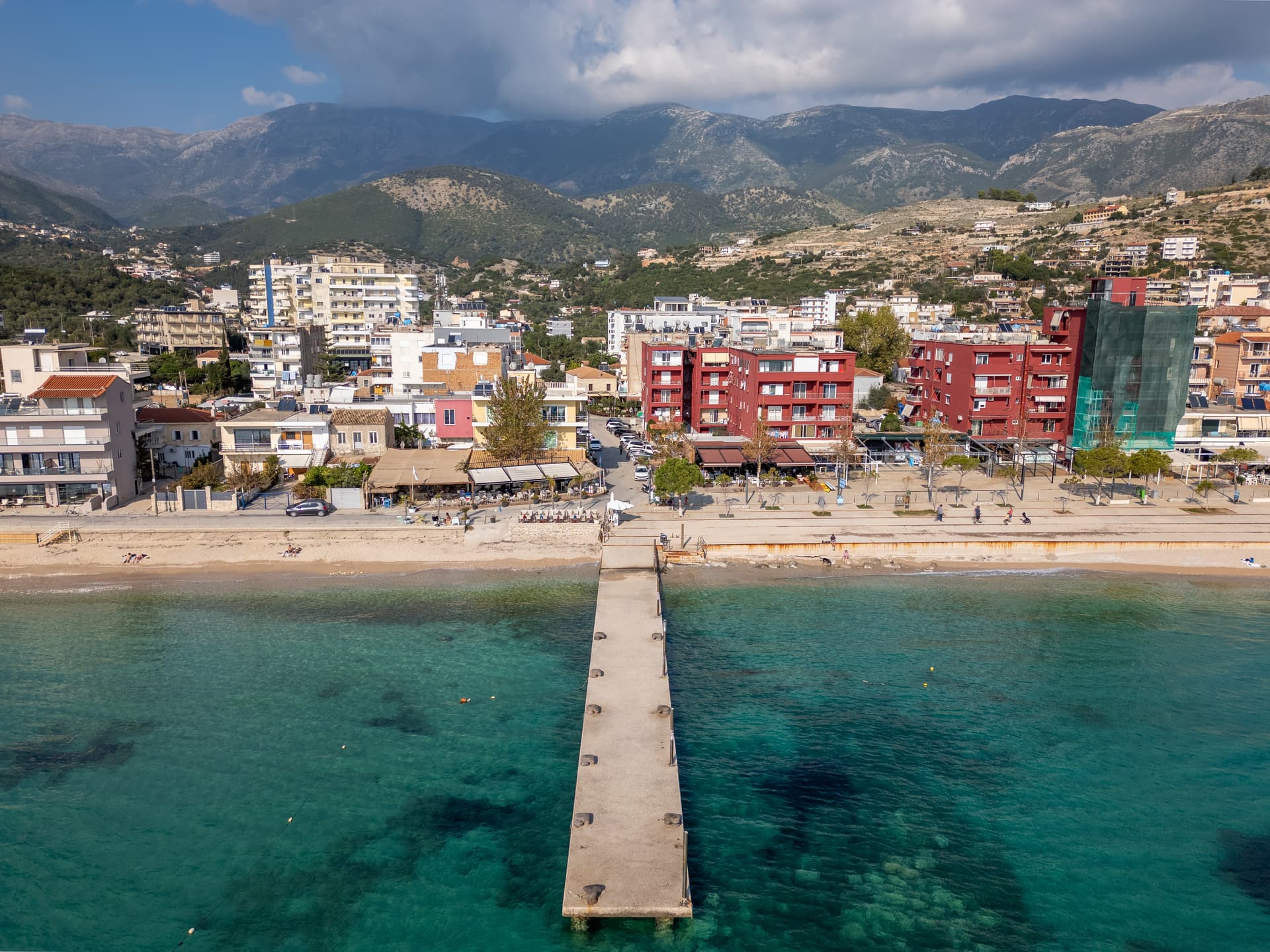 Coastal town in Himare, Albania with buildings backed by steep mountains and clear turquoise water.