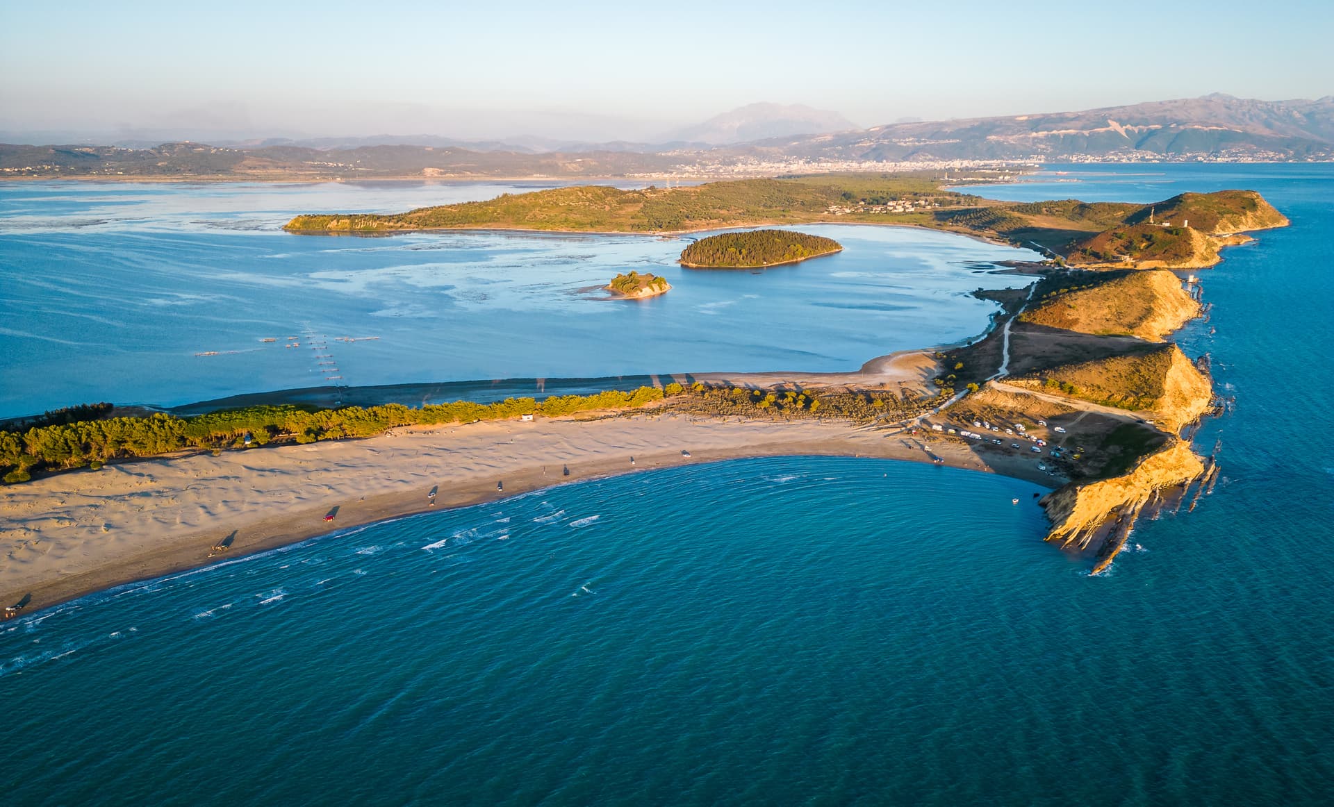 Aerial view of Dalan Beach near Vlorë, showing sandy shore, turquoise sea, and distant mountains.