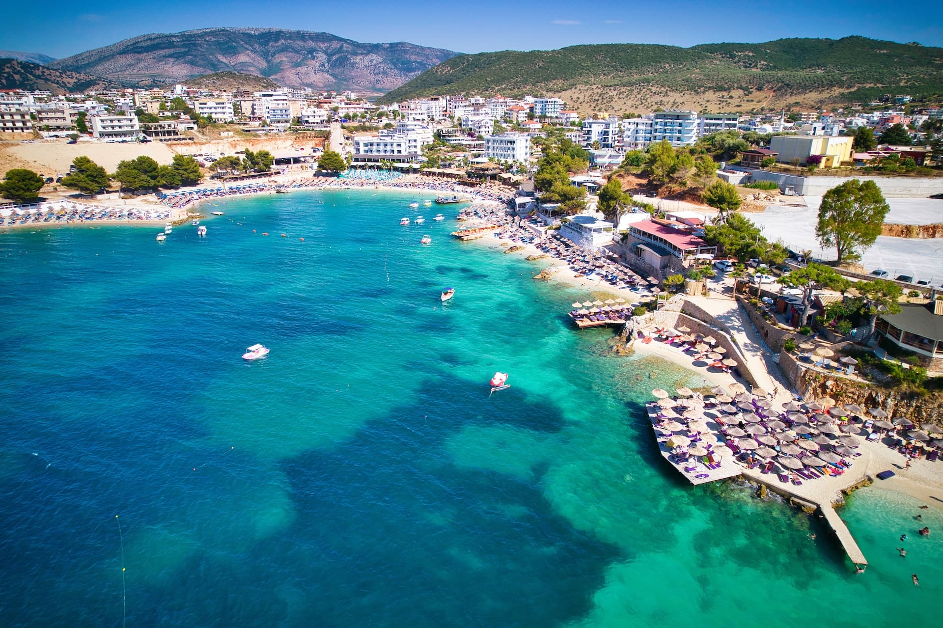 Coastal town of Sarande, Southern Albania with turquoise sea and beach umbrellas.