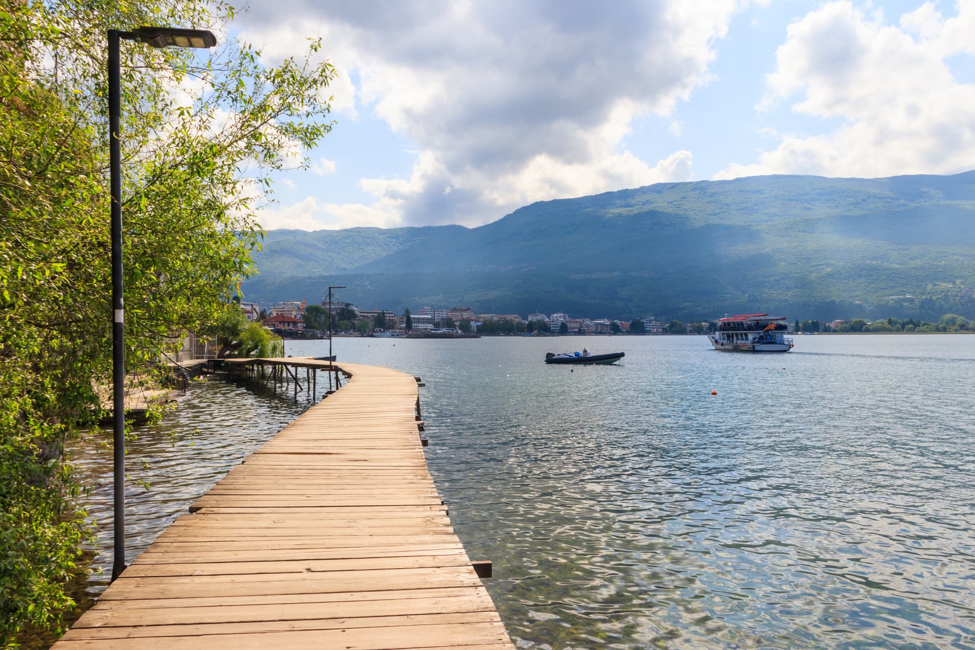 Wooden pier on Lake Ohrid, North Macedonia, with boats and mountains in background.